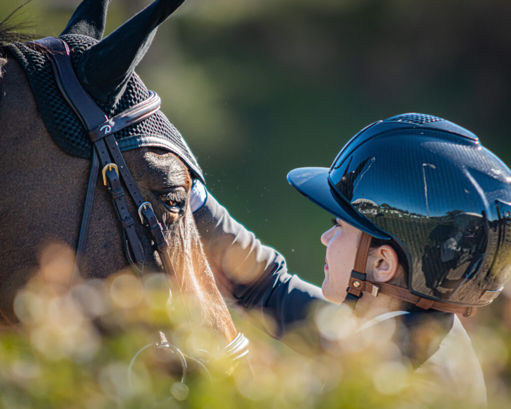 Rider beside a horse in a quiet moment away from the arena.
